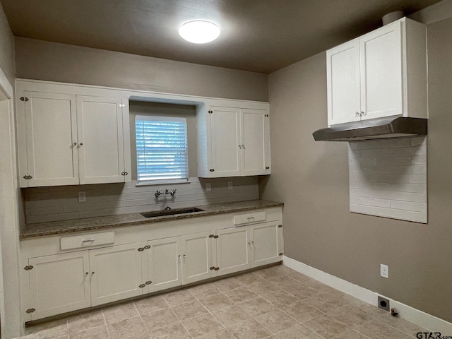 kitchen with tasteful backsplash, white cabinetry, dark stone counters, and sink