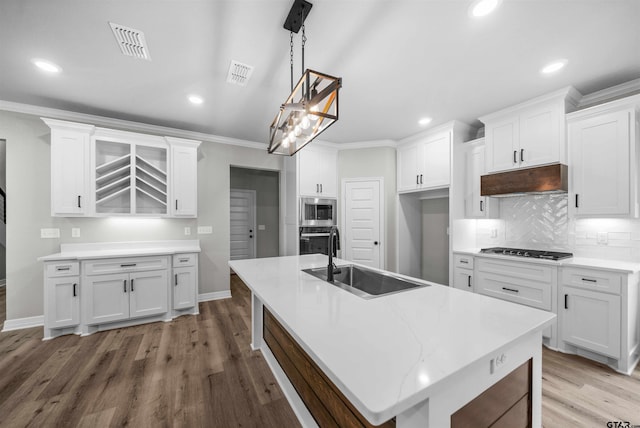 kitchen with white cabinets, a center island with sink, sink, hanging light fixtures, and stainless steel appliances