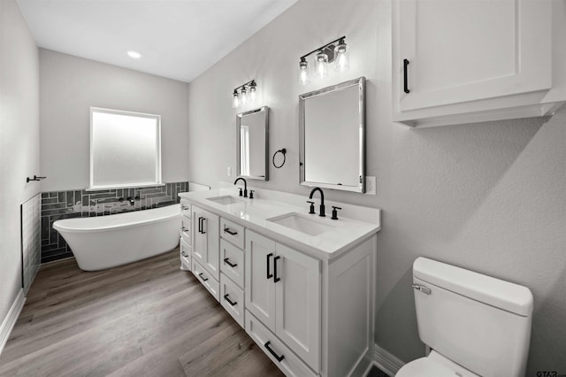 bathroom with a bath, hardwood / wood-style floors, toilet, vanity, and tile walls