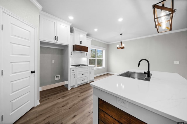 kitchen featuring white cabinets, pendant lighting, crown molding, and sink