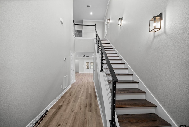 stairway featuring hardwood / wood-style flooring, ceiling fan, and crown molding