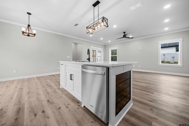 kitchen featuring stainless steel dishwasher, a kitchen island with sink, sink, decorative light fixtures, and white cabinetry