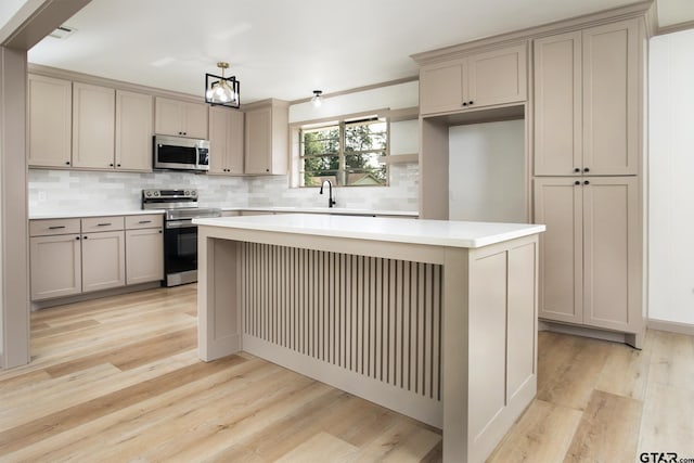 914 Neches Dr, Tyler, TX 75702 - kitchen featuring appliances with stainless steel finishes, light wood-type flooring, backsplash, and a center island