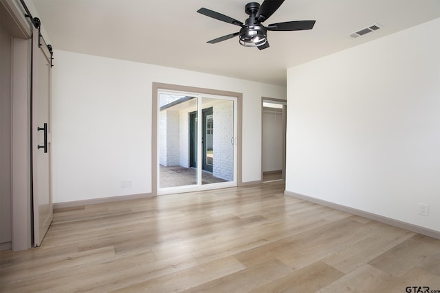 914 Neches Dr, Tyler, TX 75702 - empty room featuring a barn door, ceiling fan, and light wood-style flooring