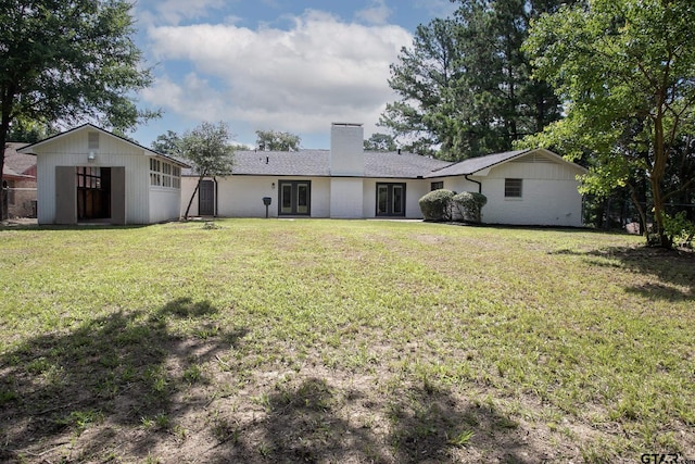 914 Neches Dr, Tyler, TX 75702 - rear view of house with french doors, a chimney, a lawn, and an outbuilding