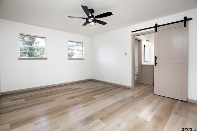 914 Neches Dr, Tyler, TX 75702 - spare room with a barn door, ceiling fan, and light wood-type flooring