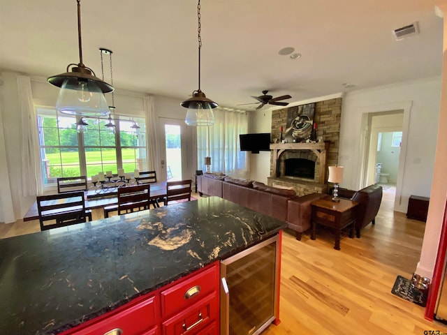 kitchen with hanging light fixtures, light hardwood / wood-style floors, ceiling fan, and wine cooler