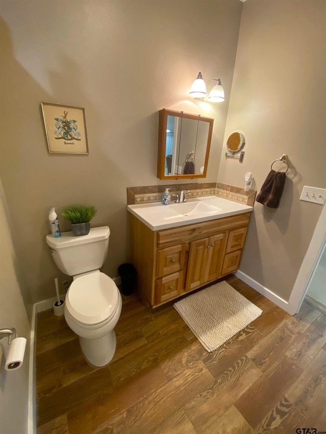 bathroom featuring toilet, vanity, and hardwood / wood-style flooring