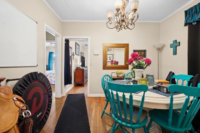 dining room with light hardwood / wood-style floors, ornamental molding, and an inviting chandelier