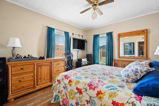 bedroom featuring ceiling fan, crown molding, and wood-type flooring