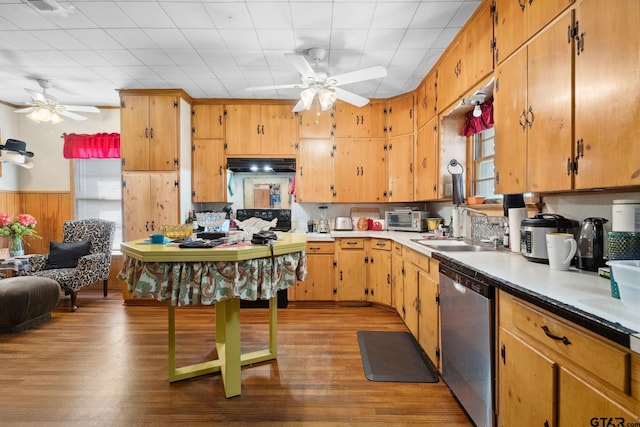 kitchen with wood walls, sink, stainless steel dishwasher, ceiling fan, and light hardwood / wood-style floors