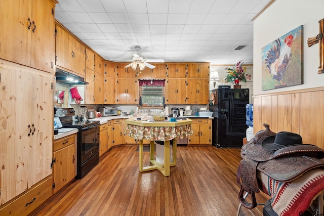 kitchen with black appliances, ceiling fan, light hardwood / wood-style floors, and wooden walls