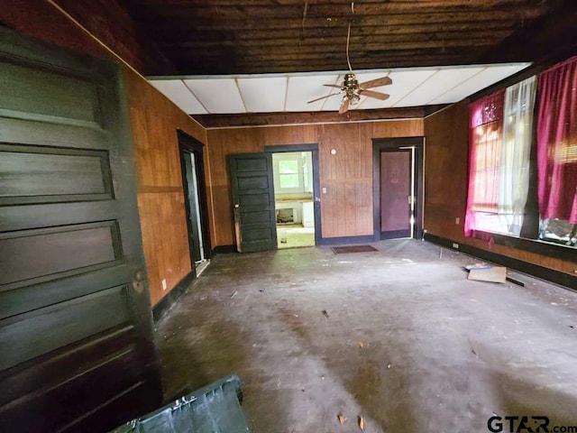 823 W Louisiana St, Palestine, TX 75801 - unfurnished living room featuring unfinished concrete floors, wood walls, and a ceiling fan