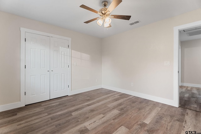 unfurnished bedroom with hardwood / wood-style floors, ceiling fan, and a closet