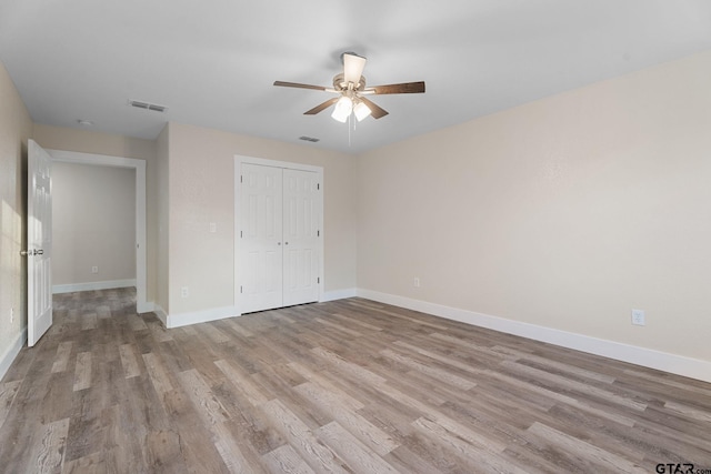 unfurnished bedroom with ceiling fan, light hardwood / wood-style floors, and a closet