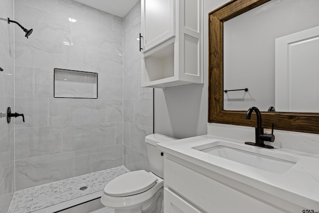 bathroom featuring tiled shower, vanity, and toilet