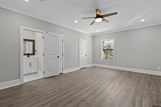 unfurnished bedroom featuring ensuite bathroom, sink, crown molding, hardwood / wood-style flooring, and ceiling fan