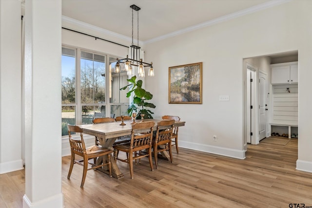 dining space featuring crown molding, plenty of natural light, an inviting chandelier, and light wood-type flooring