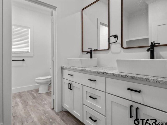 12237 Harlon St, Flint, TX 75762 - full bathroom featuring toilet, double vanity, a sink, and wood finished floors