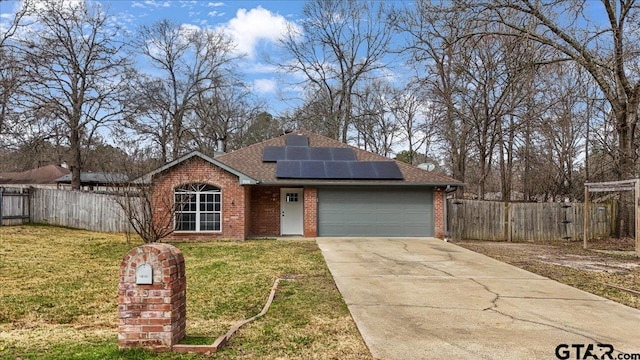 ranch-style house with a garage, a front yard, and solar panels