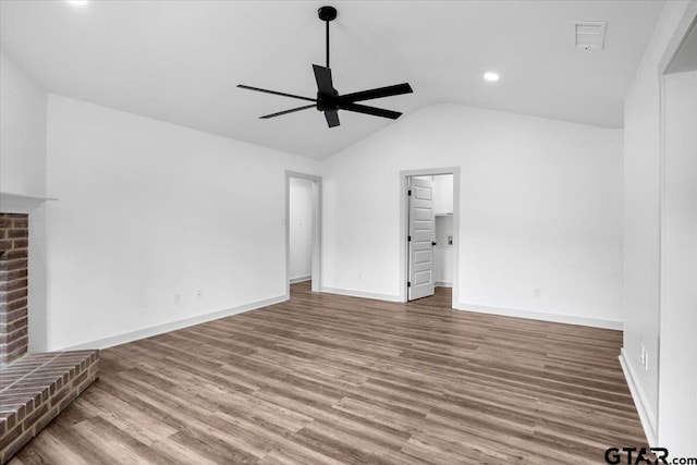 unfurnished living room featuring wood-type flooring, vaulted ceiling, a fireplace, and ceiling fan