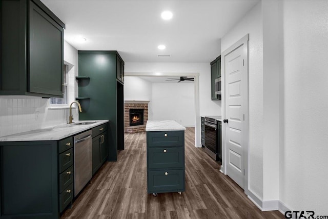 kitchen with appliances with stainless steel finishes, a fireplace, sink, dark hardwood / wood-style flooring, and decorative backsplash