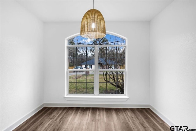 unfurnished dining area with an inviting chandelier and dark hardwood / wood-style flooring