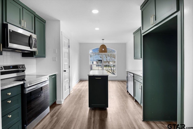 kitchen featuring appliances with stainless steel finishes, backsplash, hanging light fixtures, green cabinetry, and light stone countertops