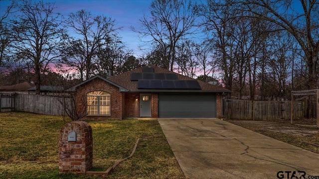 view of front facade featuring a garage, a yard, and solar panels