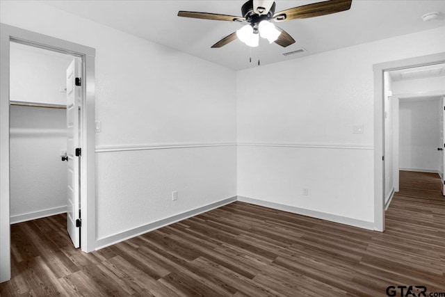 unfurnished bedroom with a closet, dark hardwood / wood-style floors, ceiling fan, and a spacious closet