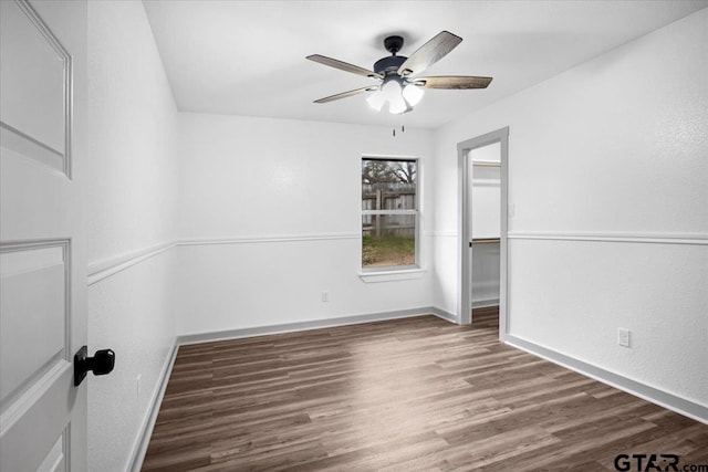 empty room with ceiling fan and dark hardwood / wood-style flooring