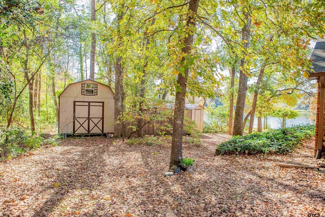 view of yard featuring a storage shed and a water view