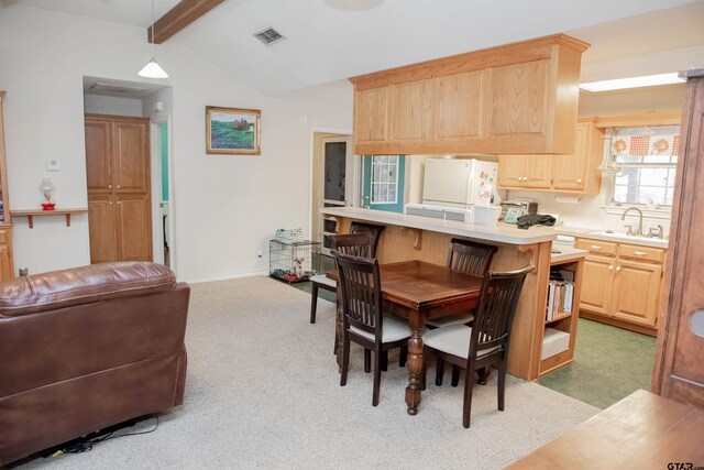 carpeted dining area featuring vaulted ceiling with beams