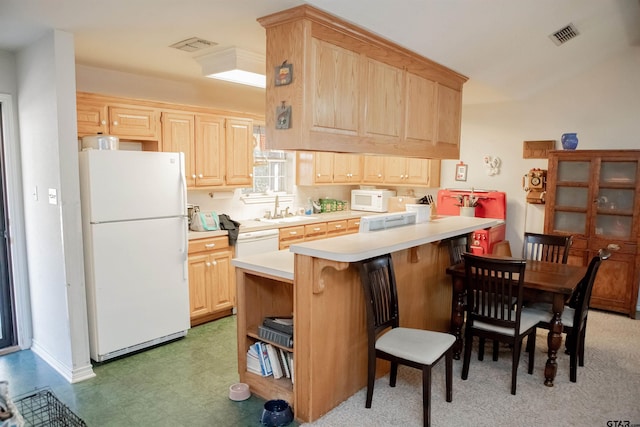 kitchen featuring a kitchen bar, kitchen peninsula, sink, light brown cabinetry, and white appliances