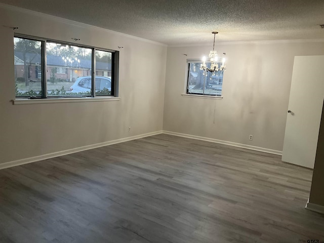 spare room with wood finished floors, baseboards, an inviting chandelier, a textured ceiling, and crown molding