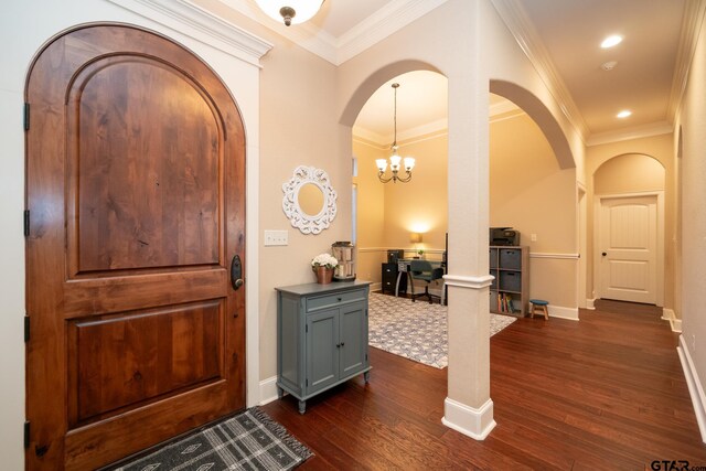 foyer featuring decorative columns, a chandelier, ornamental molding, and dark hardwood / wood-style floors