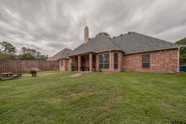 rear view of property featuring a lawn