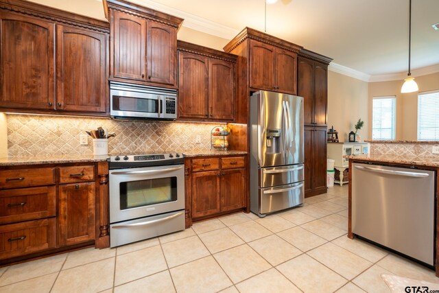 kitchen with backsplash, light tile patterned flooring, light stone counters, and appliances with stainless steel finishes