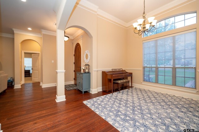 interior space with dark wood-type flooring, a chandelier, ornate columns, and ornamental molding