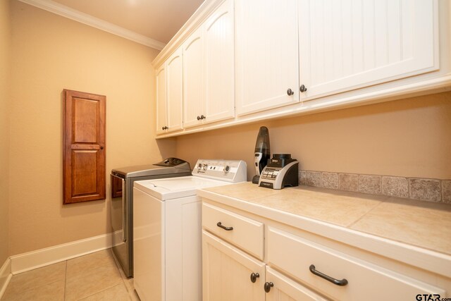 washroom featuring cabinets, separate washer and dryer, light tile patterned floors, and ornamental molding