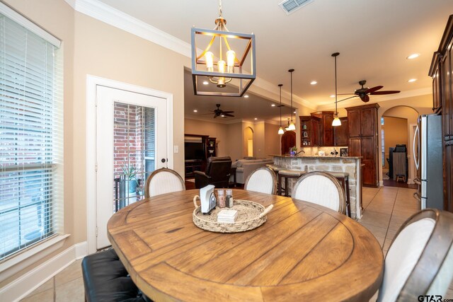 dining area featuring ceiling fan with notable chandelier, light tile patterned floors, and crown molding