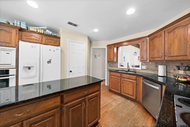 kitchen featuring dark stone countertops, white appliances, sink, and light hardwood / wood-style flooring