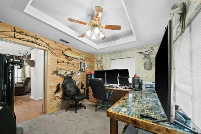 office with carpet, wood walls, ceiling fan, and a tray ceiling