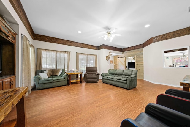 living room featuring a barn door, light hardwood / wood-style floors, and ceiling fan