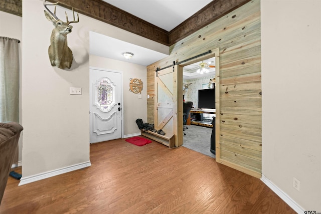 foyer featuring a barn door, hardwood / wood-style flooring, and ceiling fan