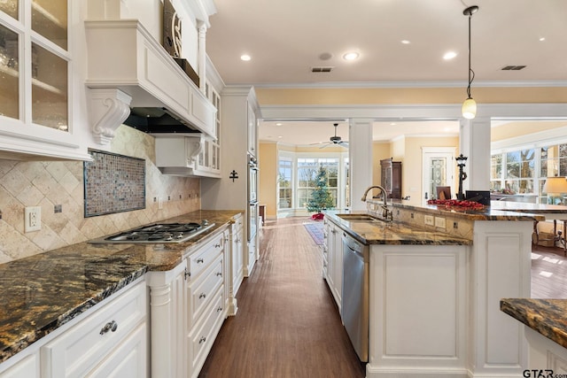 kitchen with sink, dark stone countertops, decorative light fixtures, white cabinets, and appliances with stainless steel finishes