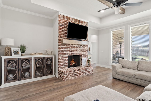 living room featuring wood-type flooring, ornamental molding, and a brick fireplace