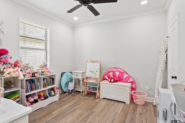 recreation room featuring light hardwood / wood-style floors, ceiling fan, and crown molding