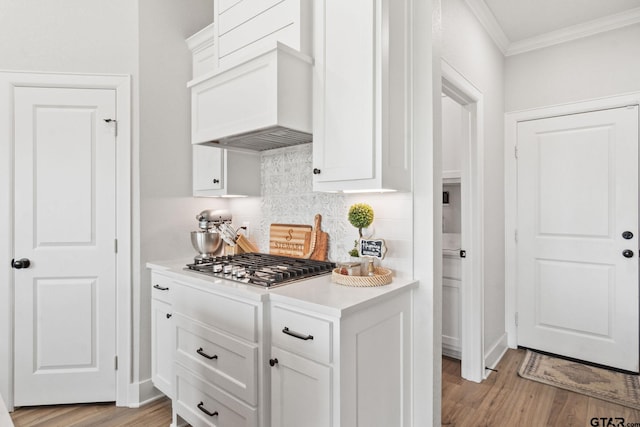 kitchen featuring white cabinets, stainless steel gas cooktop, light hardwood / wood-style floors, and backsplash