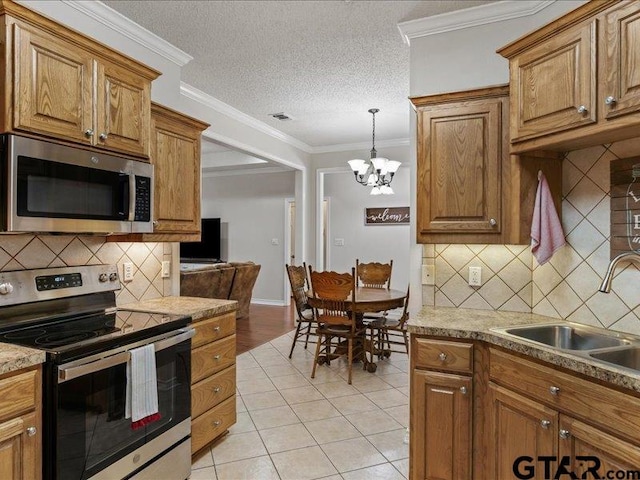 kitchen with sink, crown molding, light tile patterned floors, stainless steel appliances, and a textured ceiling